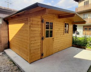 casetta in legno addossata a parete con porta a battente e finestra frontale