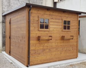 Casetta in legno addossata a parete con finestre e portavasi laterali