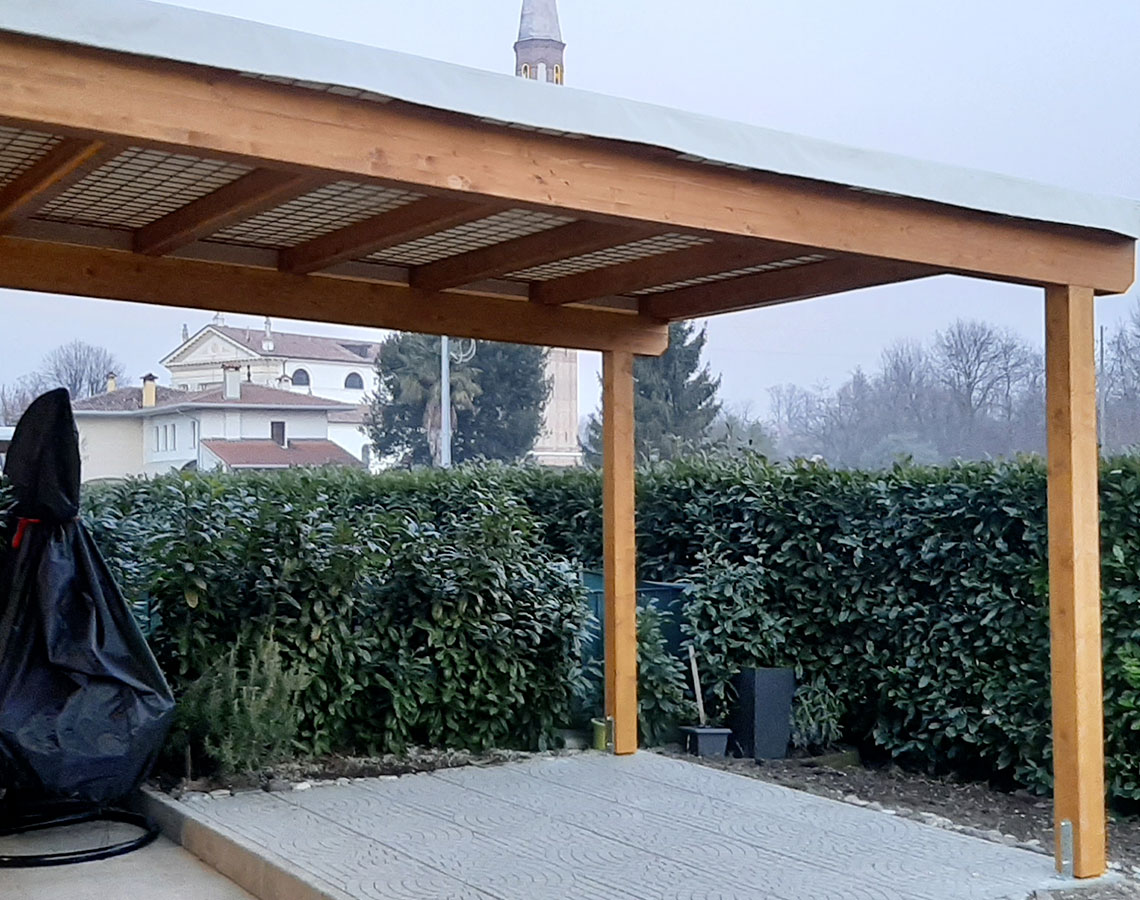 Pergolato in legno addossato a parete con copertura in telo pvc in provincia di Treviso