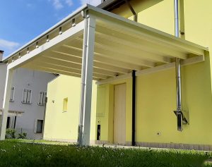 Tettoia in legno addossata a parete bianca